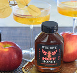 Bottle of Wild Hive Chili Sting Hot Honey with apples and fall mocktails/cocktails in the background